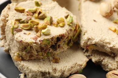 Photo of Pieces of tasty halva with pistachios on table, closeup