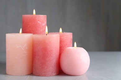 Photo of Set of different color candles burning on grey table, space for text