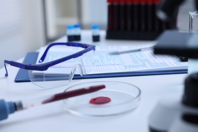 Photo of Dripping blood sample onto Petri dish on white table in laboratory, closeup