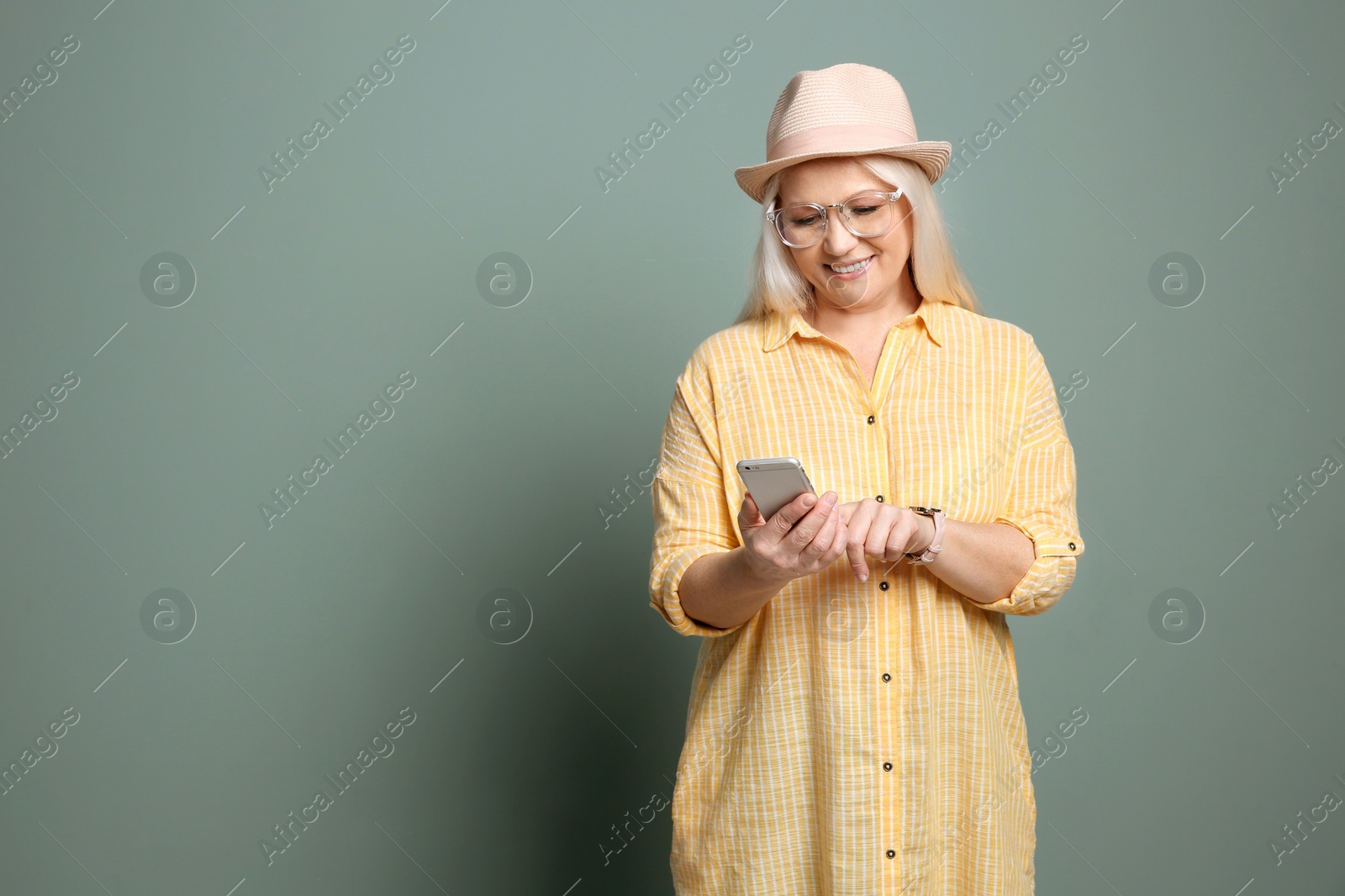 Photo of Mature woman using mobile phone on color background