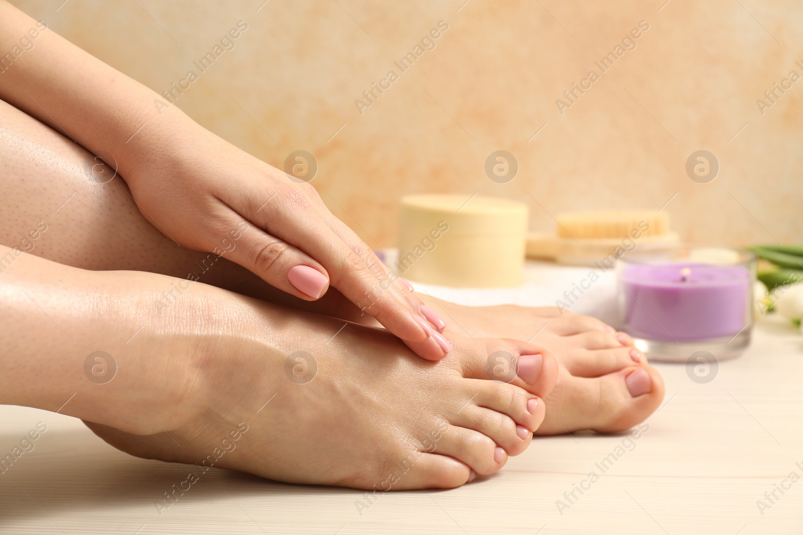 Photo of Woman with neat toenails after pedicure procedure on wooden floor, closeup