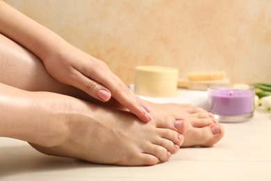 Woman with neat toenails after pedicure procedure on wooden floor, closeup