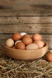 Photo of Fresh chicken eggs in bowl on dried straw bale