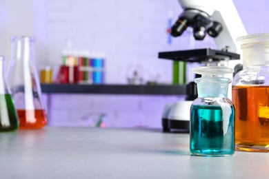 Different glassware with samples on table in chemistry laboratory. Space for text