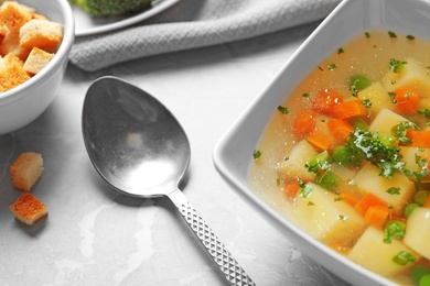 Photo of Bowl of fresh homemade vegetable soup served on grey marble table, closeup