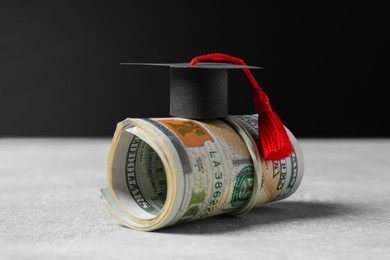 Photo of Scholarship concept. Graduation cap and banknotes on light grey table, closeup
