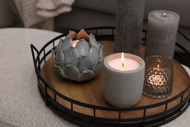 Photo of Tray with burning candles on ottoman indoors