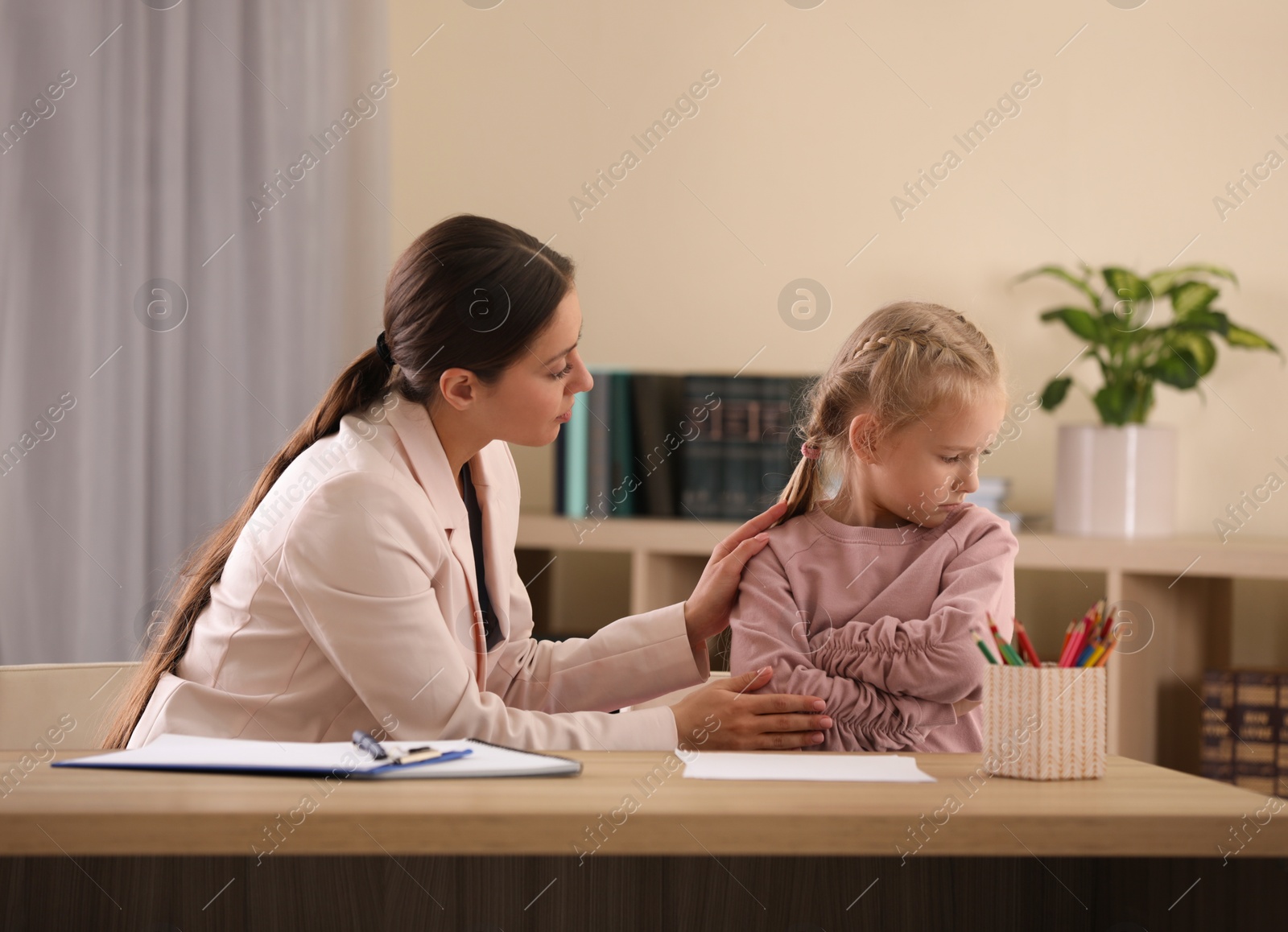 Photo of Child psychotherapist working with little girl in office