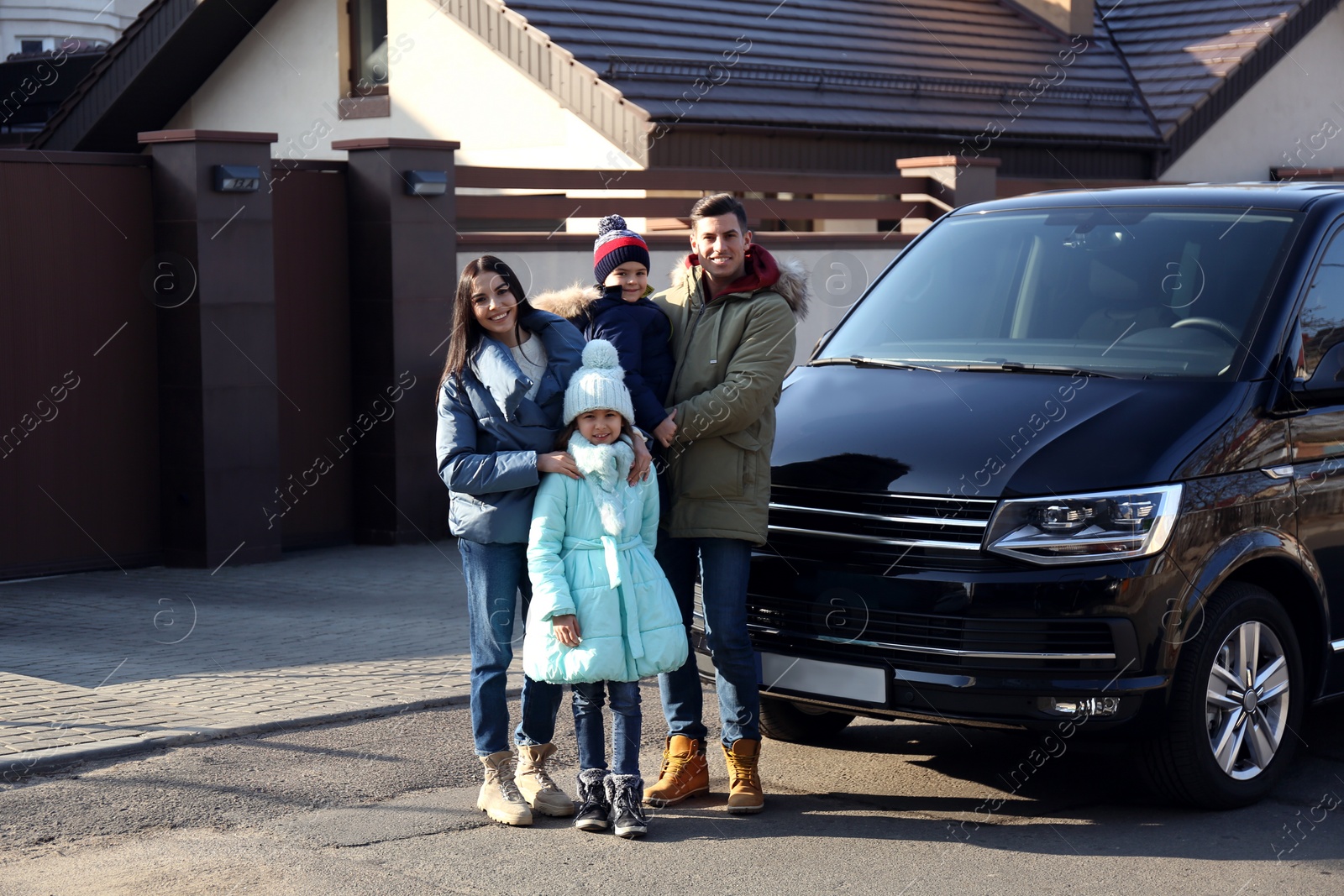 Photo of Happy family with little children near modern car on street