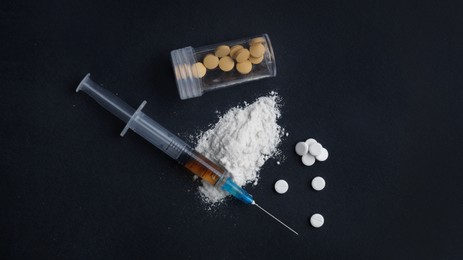 Photo of Syringe, pills and powder on black background, flat lay. Hard drugs