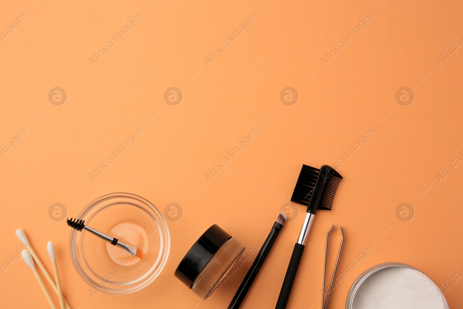 Photo of Flat lay composition with eyebrow henna and professional tools on orange background, space for text