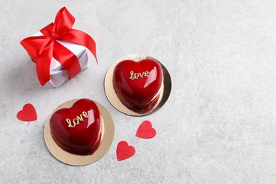 Photo of St. Valentine's Day. Delicious heart shaped cakes and gift on light table, flat lay. Space for text