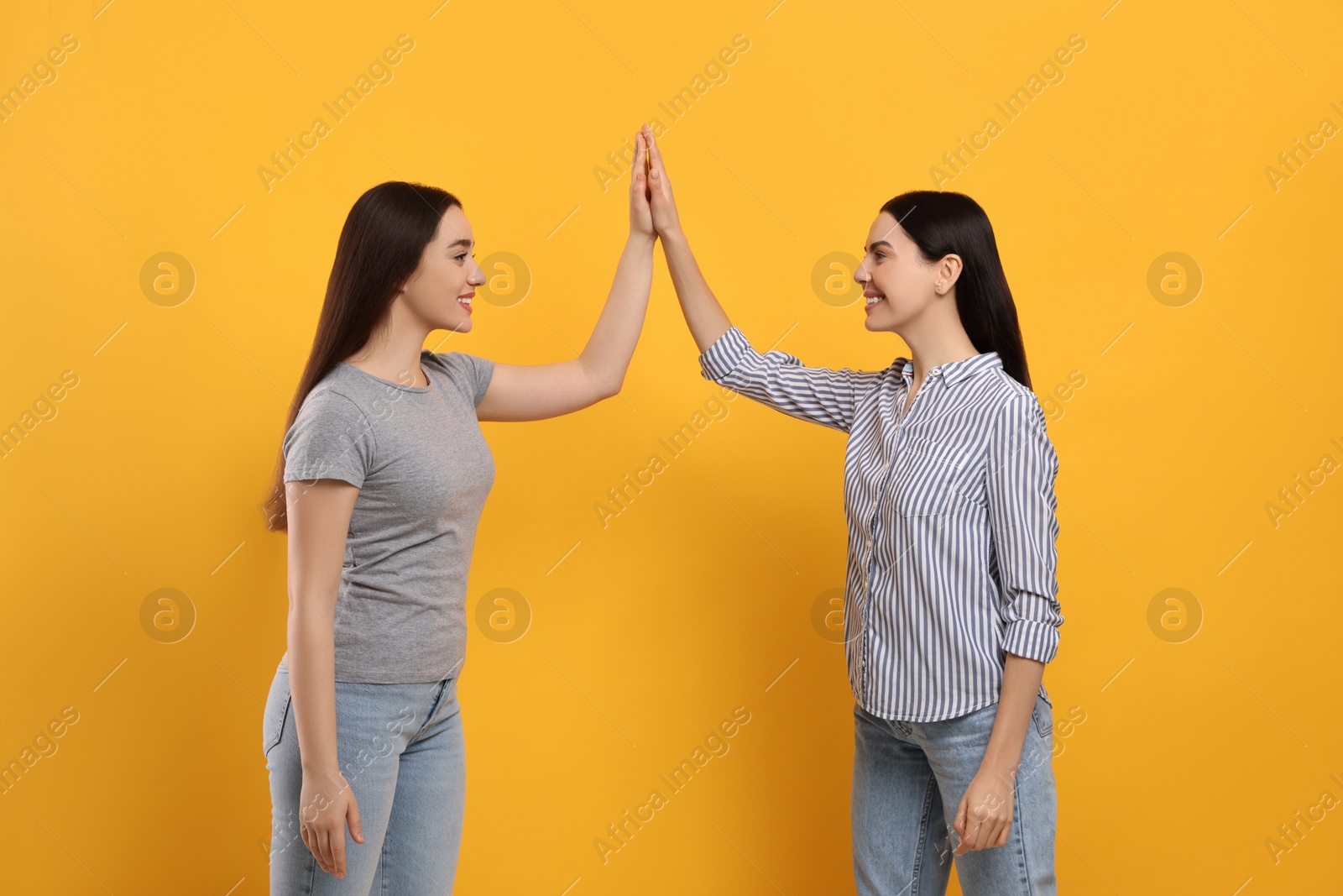 Photo of Women giving high five on orange background