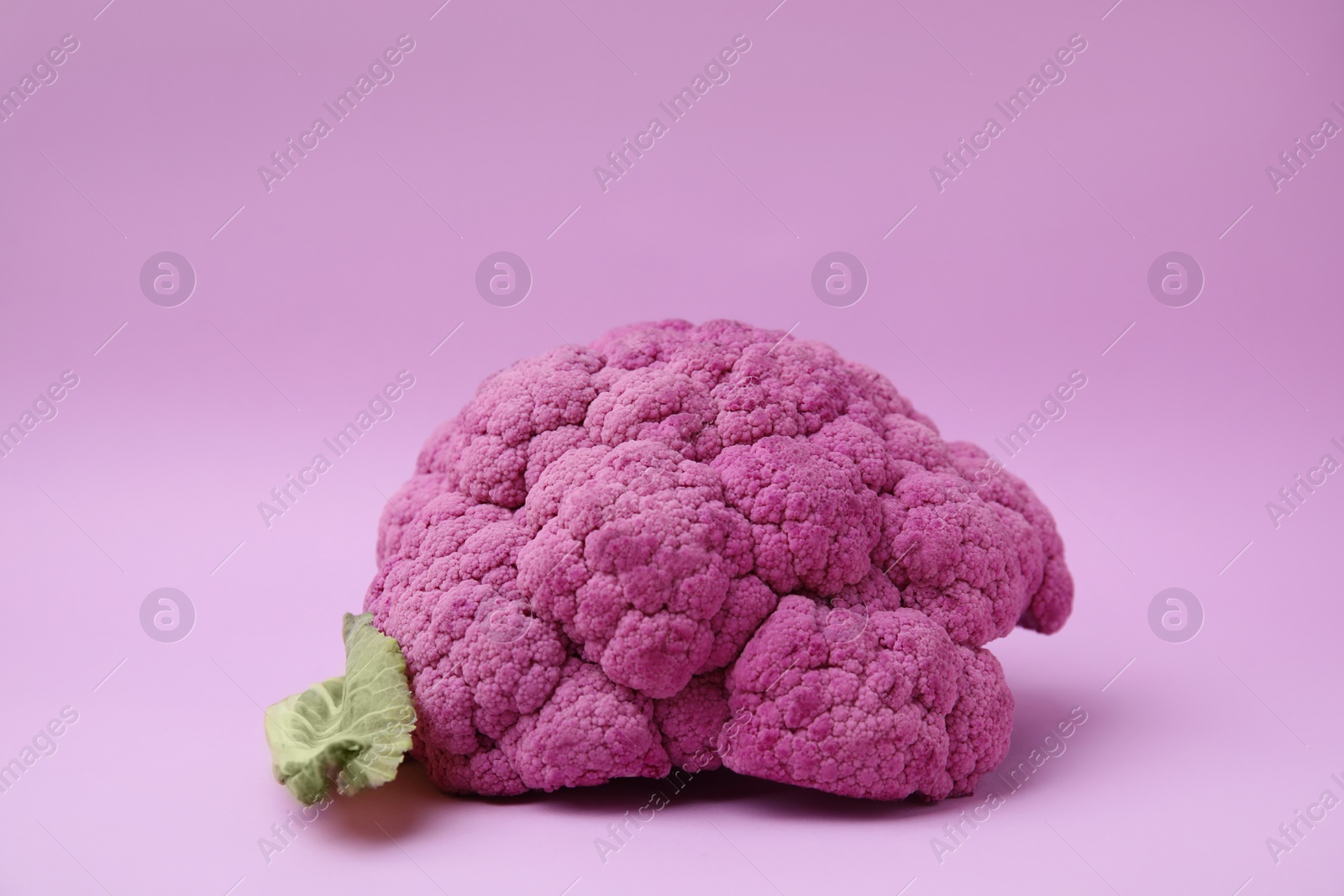 Photo of Whole fresh purple cauliflower on violet background