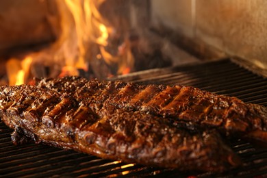 Photo of Grilling grate with tasty pork ribs in oven, closeup