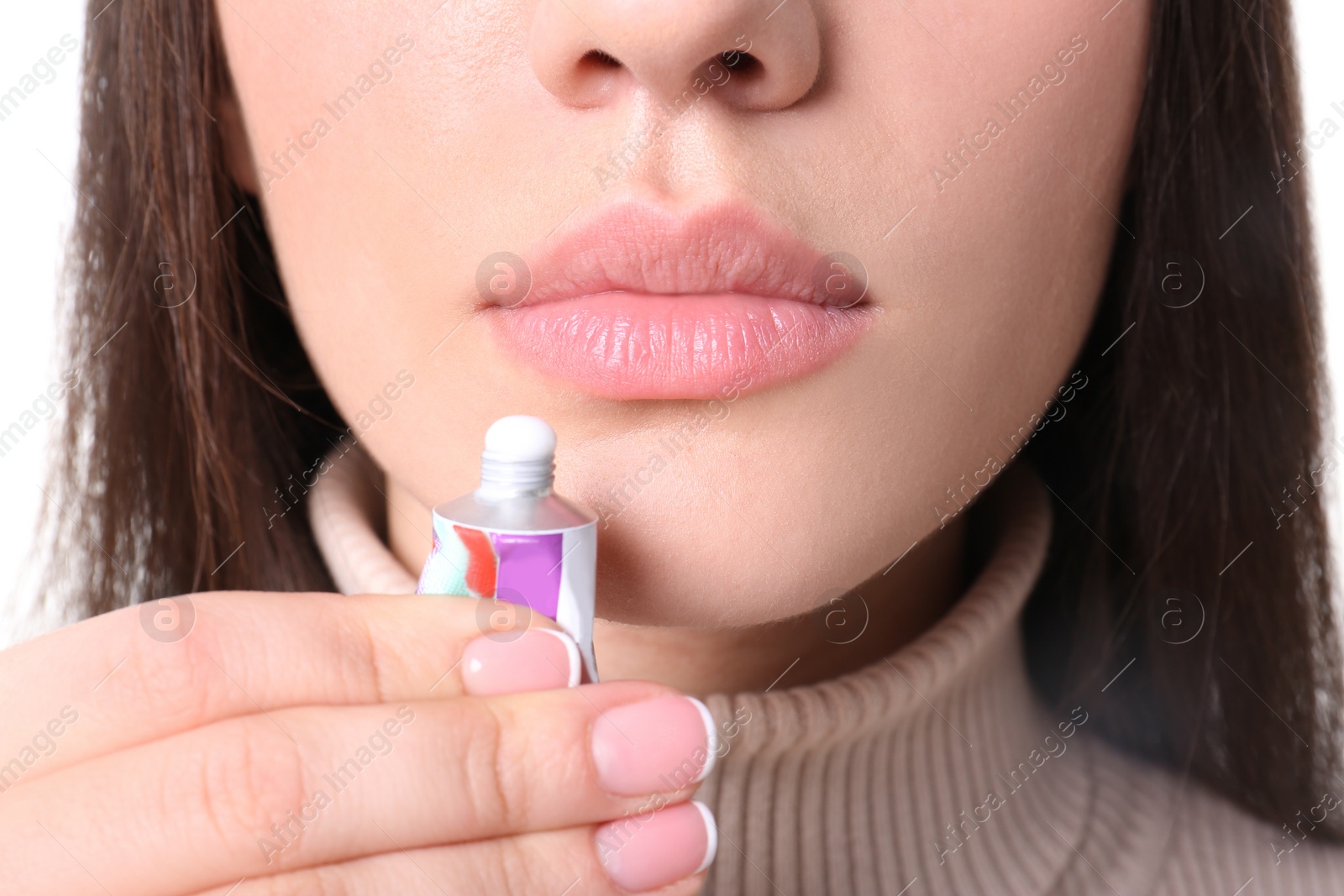 Photo of Young woman applying cold sore cream on lips, closeup