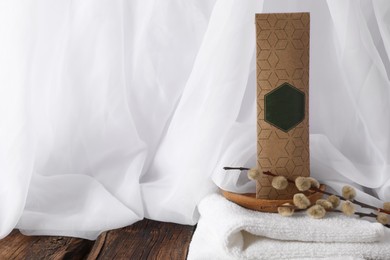 Photo of Scented sachet, pussy willow branches and towel on wooden table, space for text