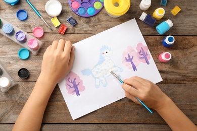 Photo of Girl painting picture of unicorn on table, top view