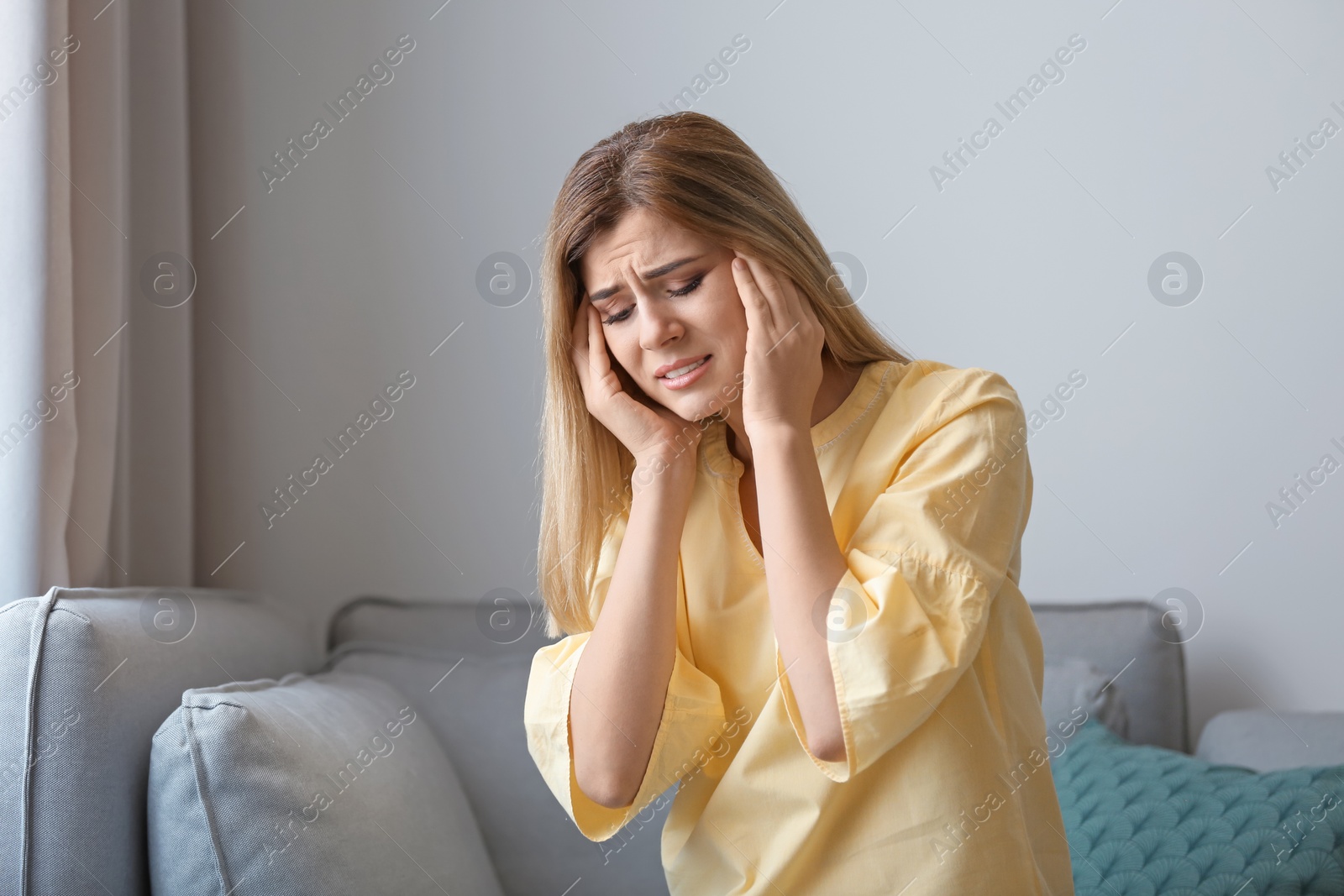 Photo of Young woman suffering from headache at home