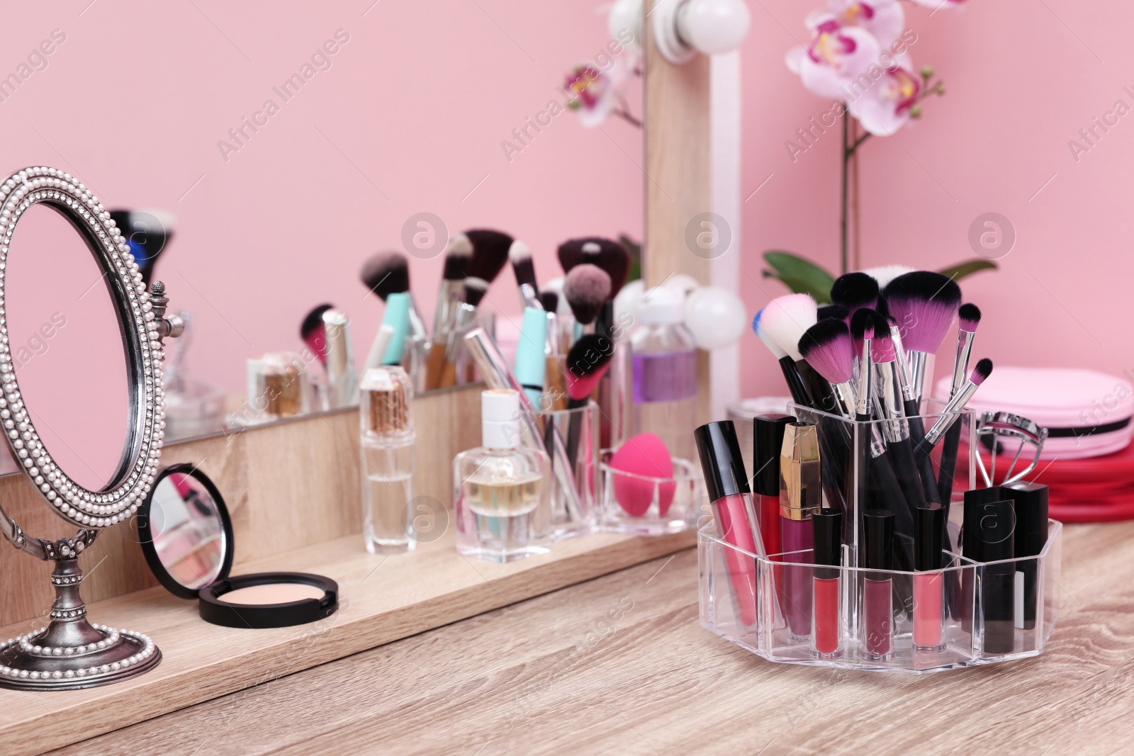 Photo of Organizer with cosmetic products for makeup on table near mirror. Space for text