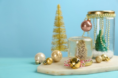 Photo of Handmade snow globe and Christmas decorations on light blue background, space for text