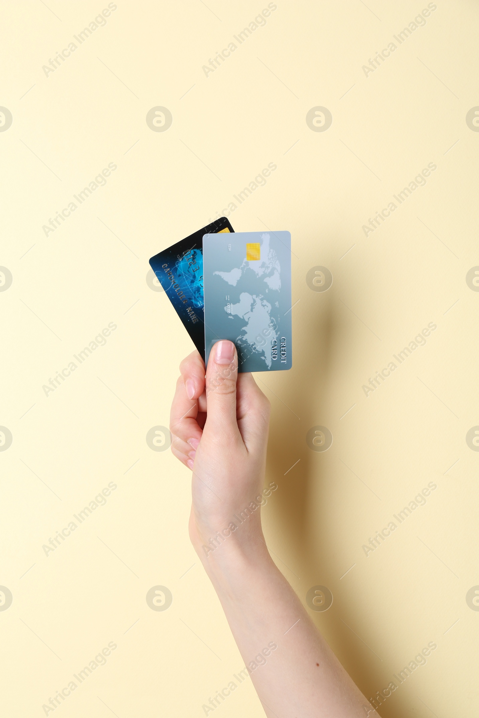 Photo of Woman holding credit cards on pale yellow background, closeup