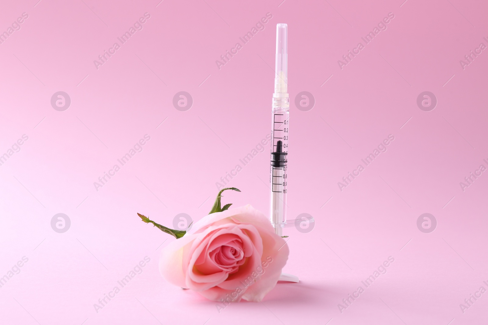 Photo of Cosmetology. Medical syringe and rose flower on pink background