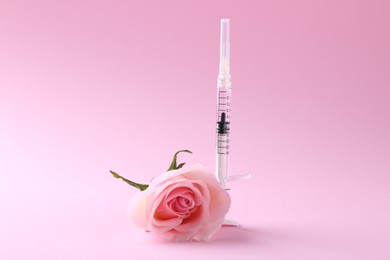 Cosmetology. Medical syringe and rose flower on pink background