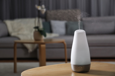 Aroma oil diffuser on wooden table indoors, space for text. Air freshener