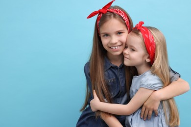 Photo of Cute little sisters on light blue background, space for text