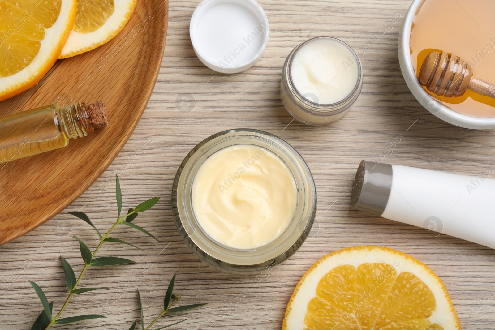 Photo of Body cream and other cosmetics with ingredients on wooden table, flat lay