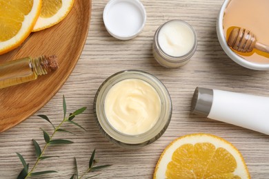 Photo of Body cream and other cosmetics with ingredients on wooden table, flat lay