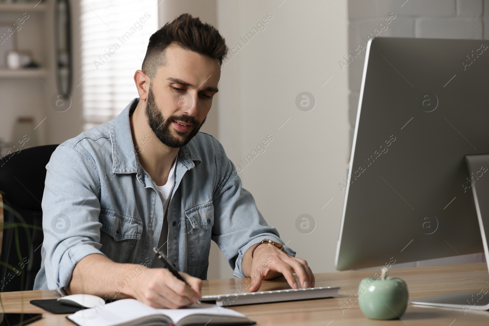 Photo of Man working with computer at table in home office