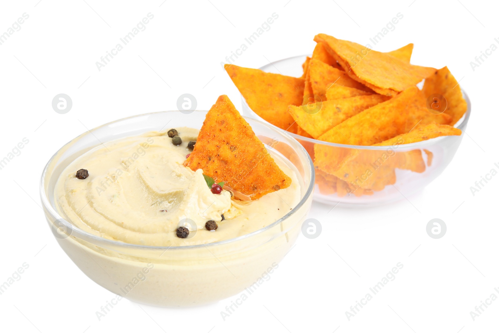 Photo of Delicious hummus and nachos in glass bowls on white background