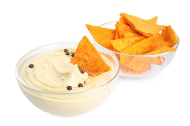 Delicious hummus and nachos in glass bowls on white background