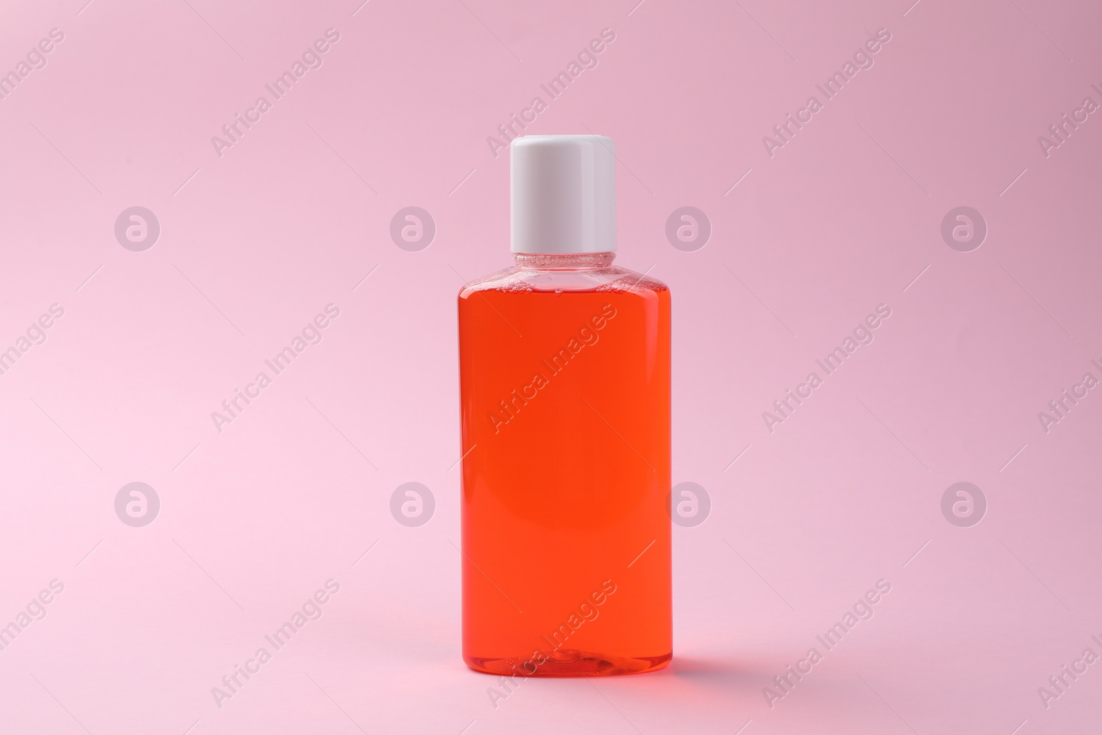 Photo of Fresh mouthwash in bottle on pink background