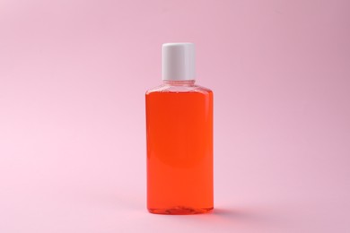 Photo of Fresh mouthwash in bottle on pink background