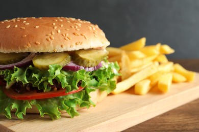 Photo of Delicious burger with beef patty and french fries on wooden table, closeup