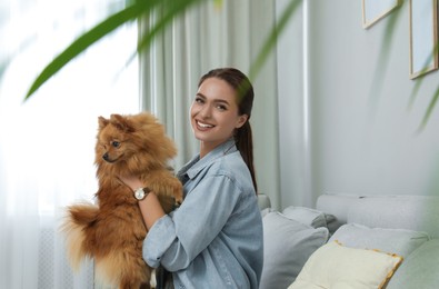 Happy young woman with cute dog at home