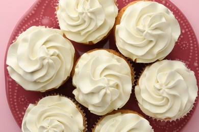 Photo of Tasty vanilla cupcakes with cream on pink background, top view