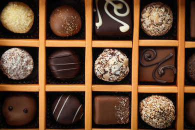 Photo of Box with different chocolate candies as background, top view