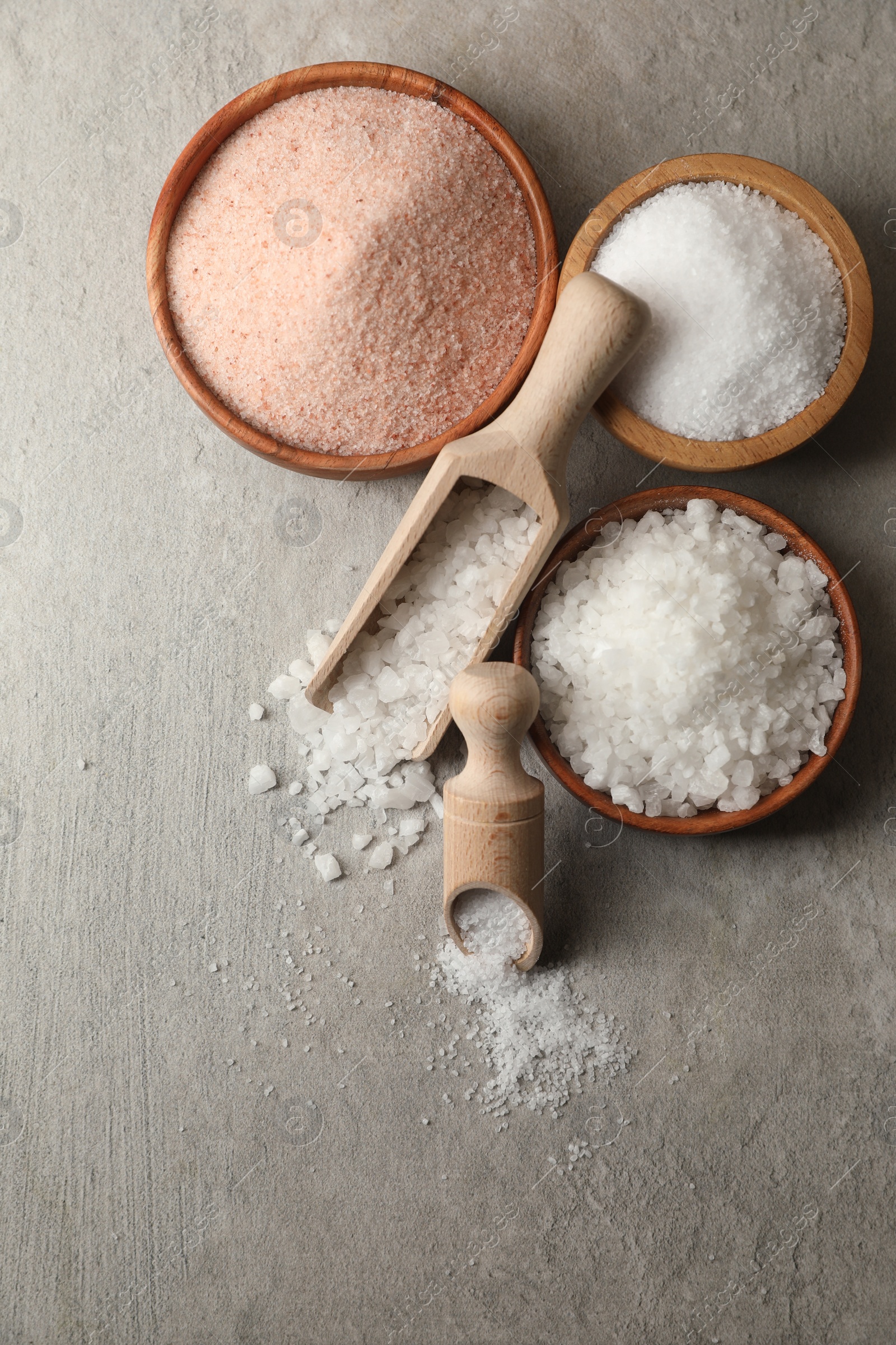 Photo of Different natural salt on grey textured table, flat lay. Space for text