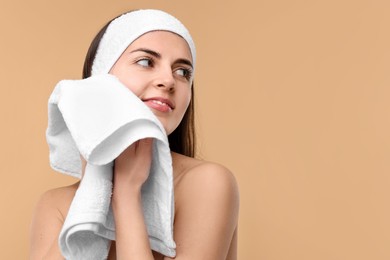 Photo of Washing face. Young woman with headband and towel on beige background, space for text