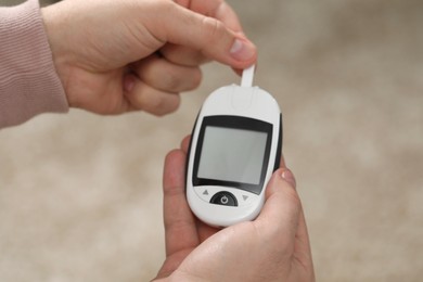 Diabetes test. Man with glucometer on blurred background, closeup