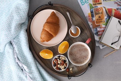 Tray with tasty breakfast on grey fabric, flat lay