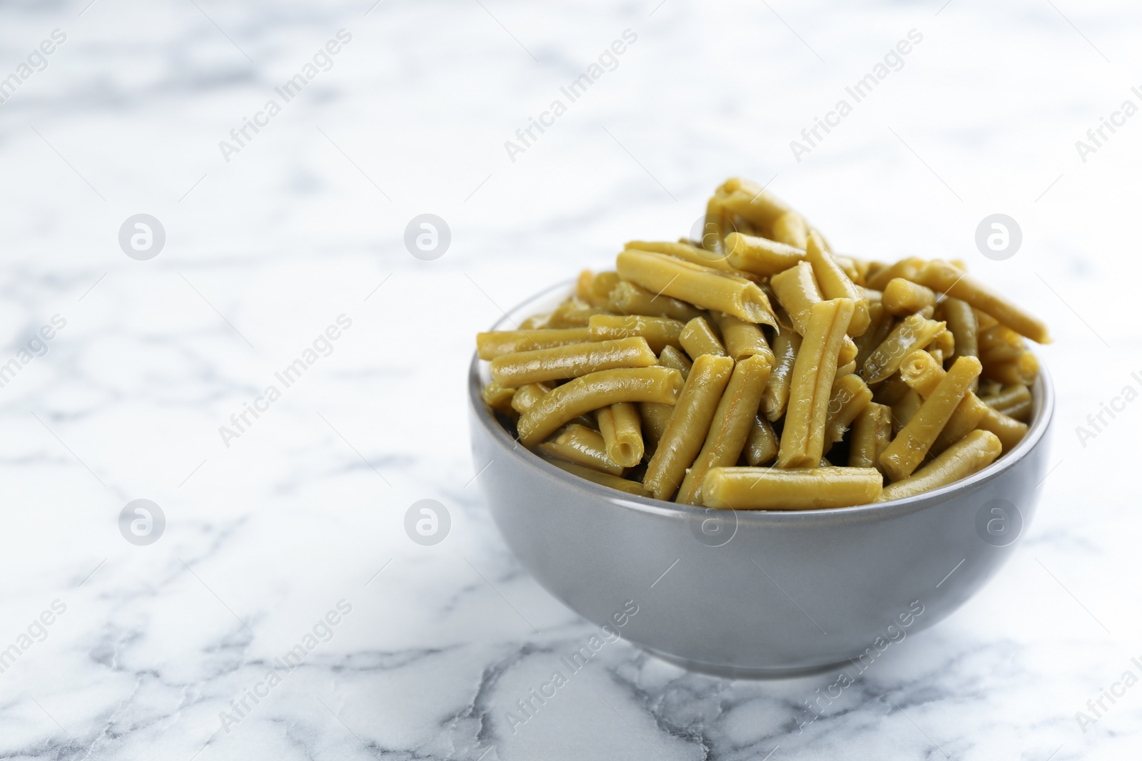 Photo of Canned green beans on white marble table. Space for text
