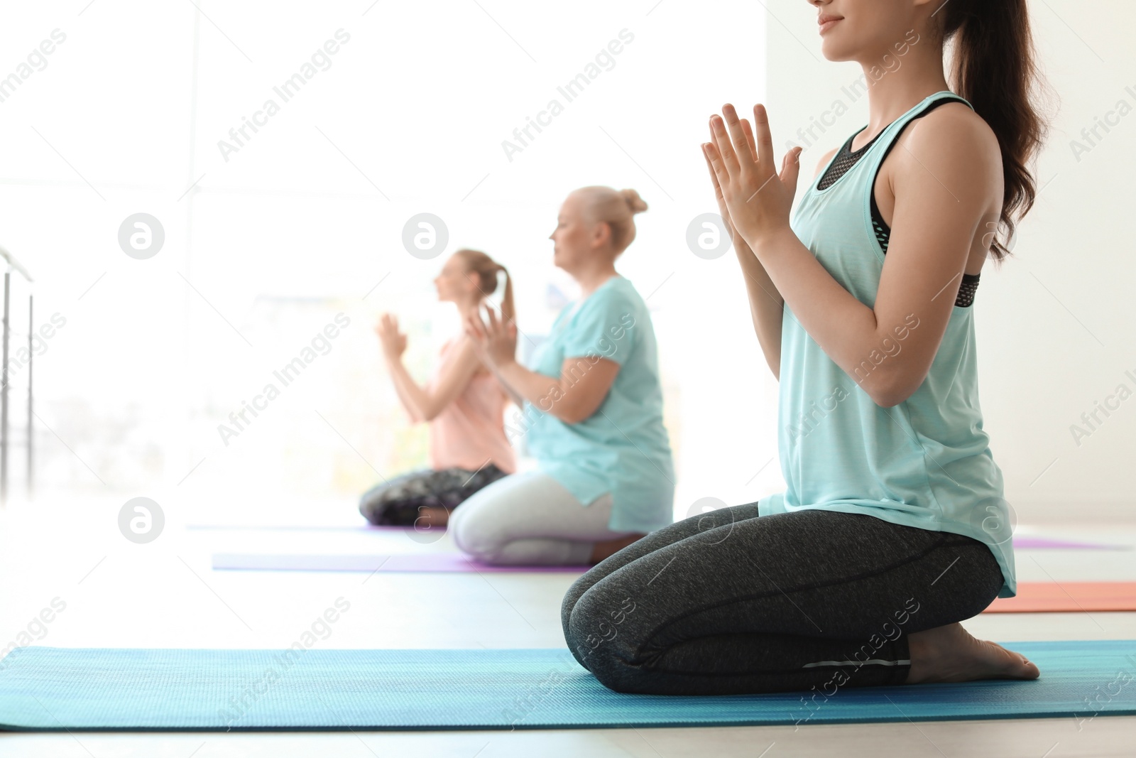 Photo of Group of women in sportswear practicing yoga indoors