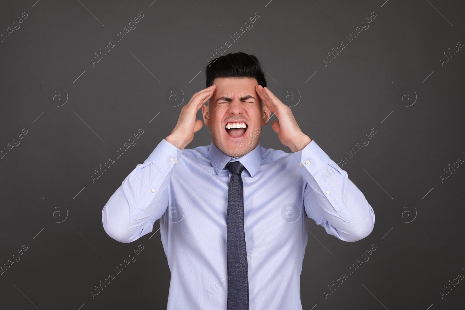 Photo of Portrait of emotional businessman on dark grey background. Personality concept