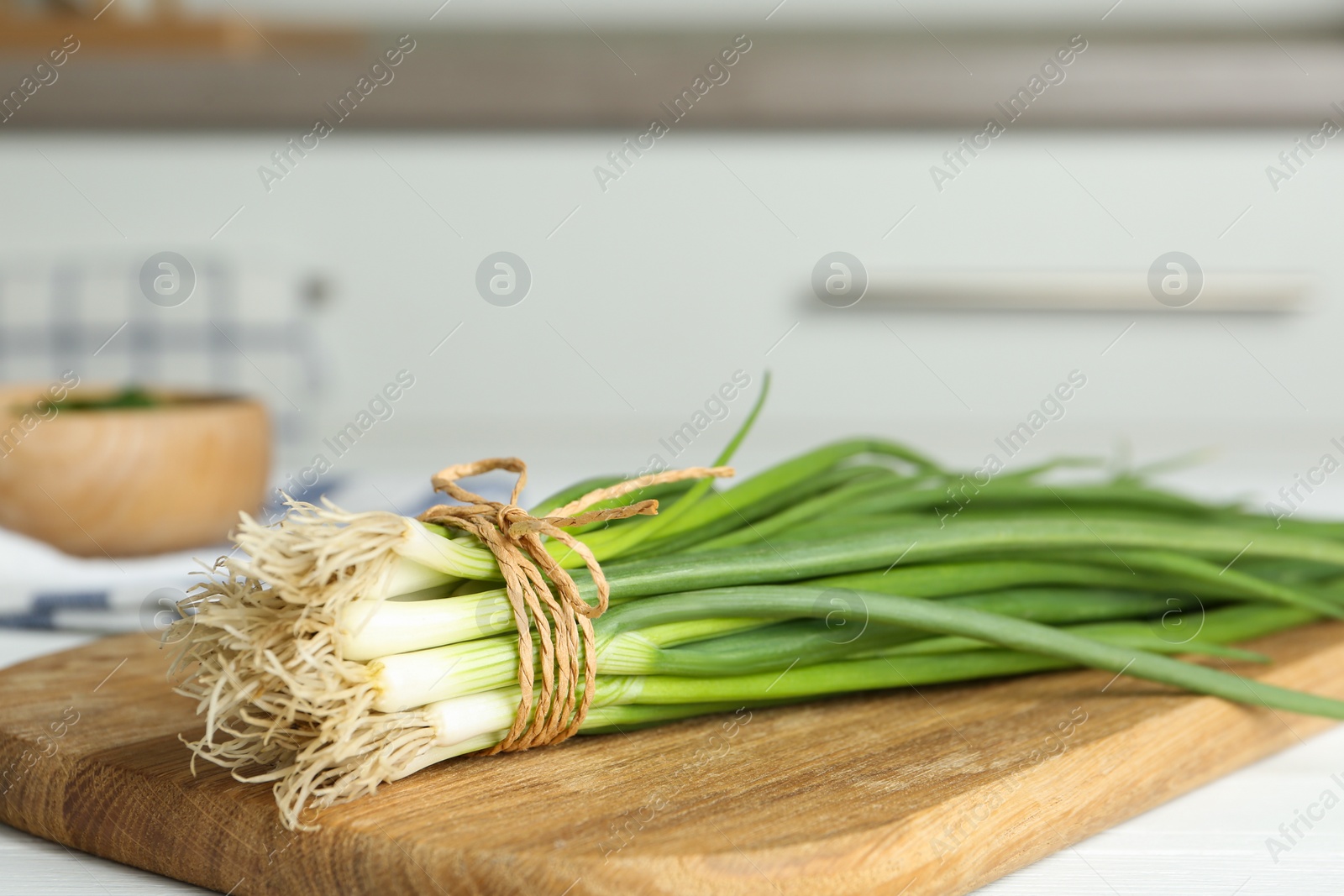 Photo of Fresh green spring onions on wooden board, closeup