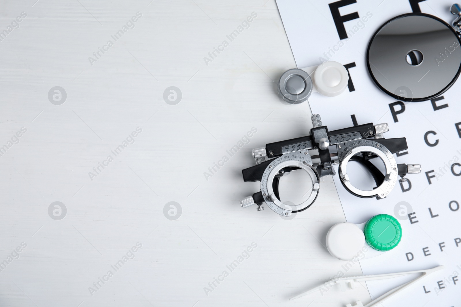 Photo of Different ophthalmologist tools on white wooden background, flat lay. Space for text